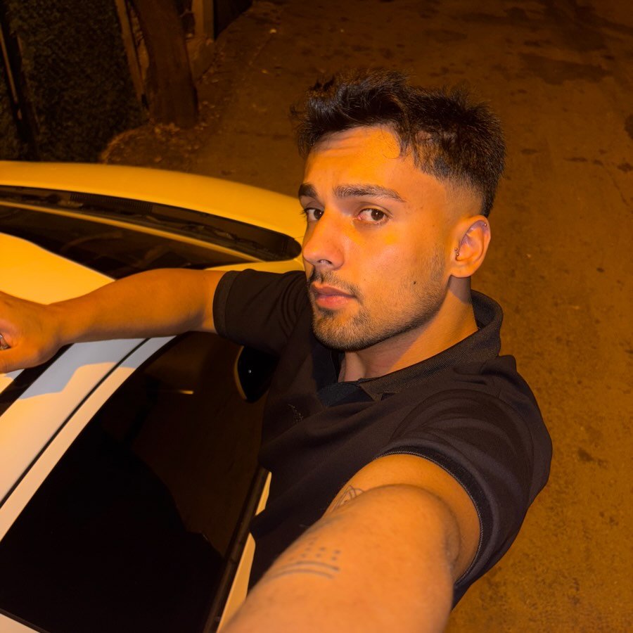 Close-up portrait of a young man with facial hair and a serious expression.