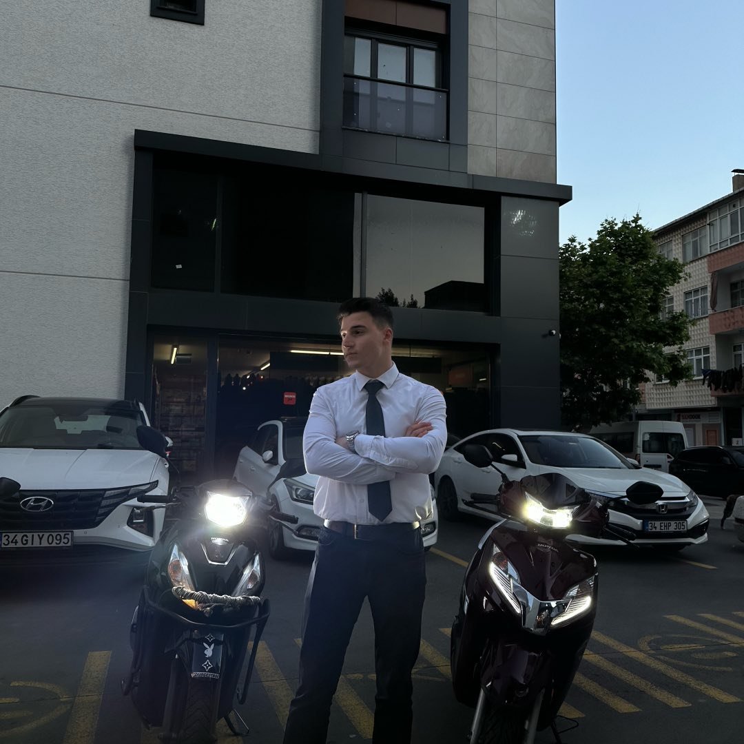 Close-up portrait of a young man with facial hair and a serious expression.